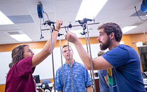 Three mechanical engineering students instructed by a professor