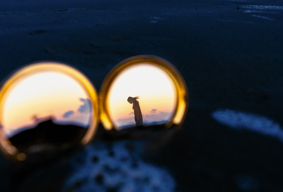 a woman's silhouette in the sunset through two small circles