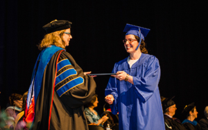 Student getting a diploma from President Huxman