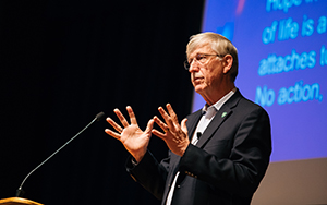 Scientist giving a lecture in front of a power point on a screen